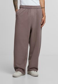 Light brown sweatpants with an elastic waistband, side pockets, and a relaxed fit. Made of soft fabric with a smooth texture.