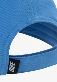 Modra kapa iz teksturirane tkanine, z ukrivljenim robom in nastavljivim trakom z črno oznako Nike.