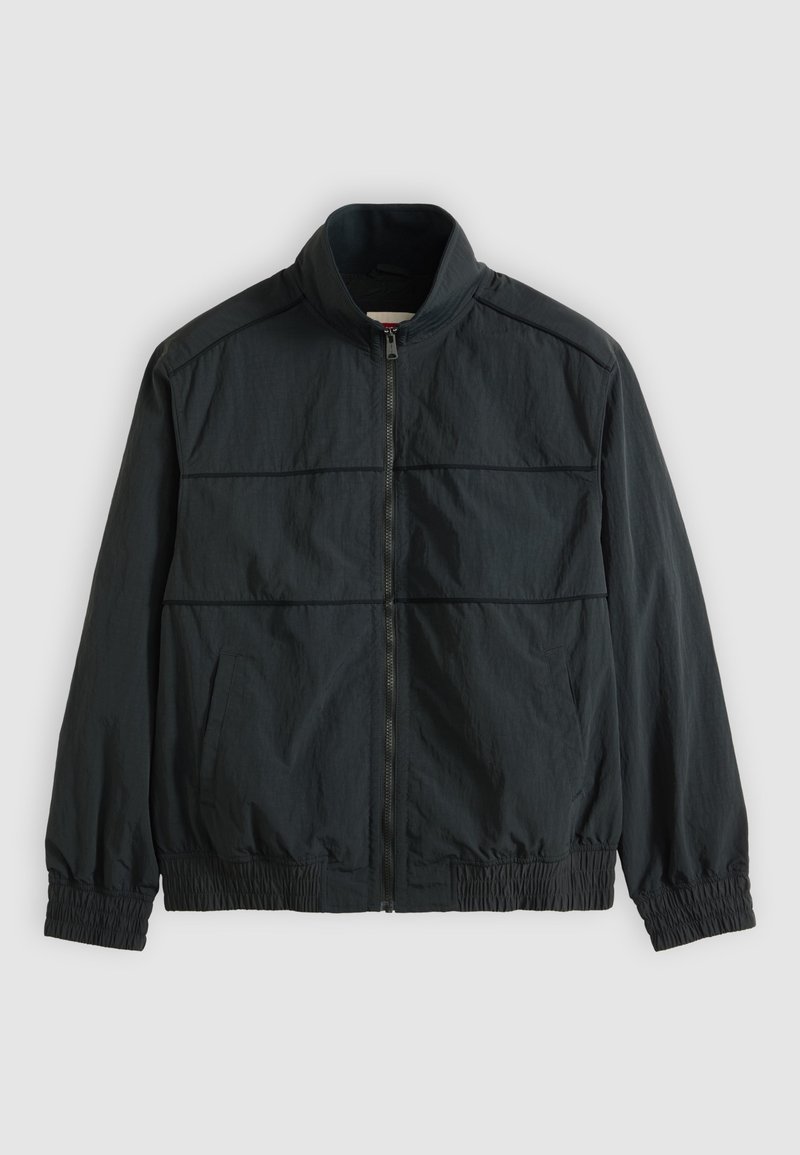 Zwarte lichte jas met rits, opstaande kraag, lange mouwen, elastische boorden en zoom, en twee voorzakken.