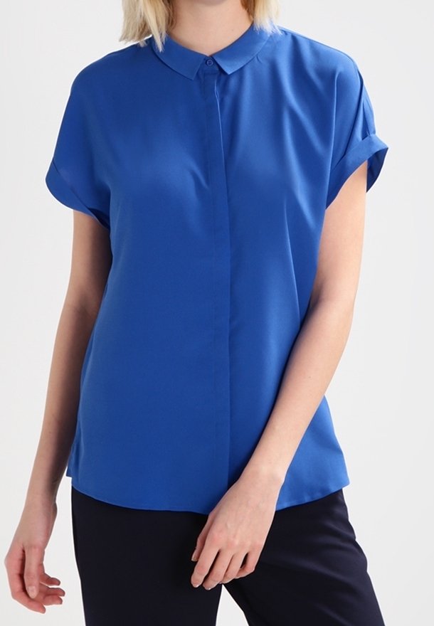Blå kortärmad blus med knäppning framtill, tillverkad av slätt tyg. Har klassisk krage och uppvikta ärmar. Skräddarsydd passform.