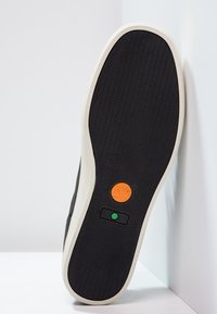 Semelle de sneaker noire avec texture en caoutchouc, semelle intermédiaire blanche, accents de marque orange et vert, et motif ondulé pour l'adhérence.