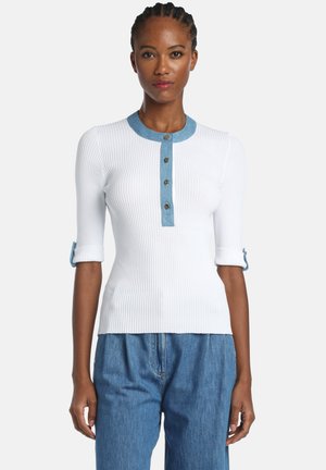Top bianco a coste con colletto in denim, quattro bottoni frontali e maniche risvoltate con dettagli con bottoni. Abbinato a pantaloni in denim blu.