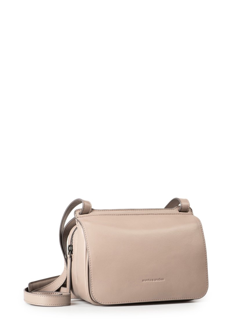 Beige Leder Crossbody-Tasche mit einem magnetischen Klappenverschluss, verstellbarem Tragegurt und dezentem Branding auf der Vorderseite. Glatte Textur, rechteckige Form.