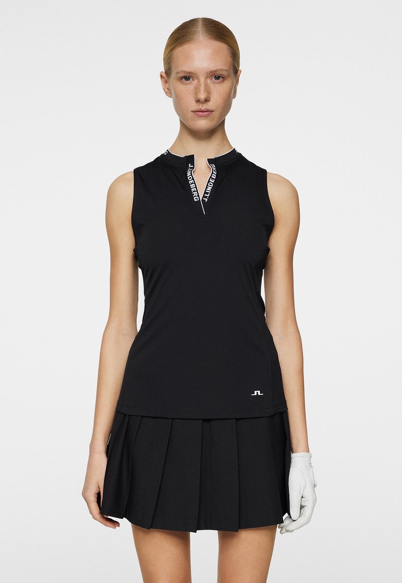 Black sleeveless top with a zippered neckline, featuring white brand detailing and a fitted silhouette, paired with a black pleated skirt.