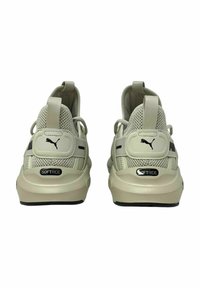 Sneaker a rete beige con suola morbida, branding prominente e un design testurizzato, dotate di un laccio sul tallone.