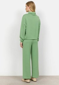 Grön, mjuk tyg lounge-set som består av en sweatshirt med hög krage och vida byxor, med en avslappnad passform och subtil textur.