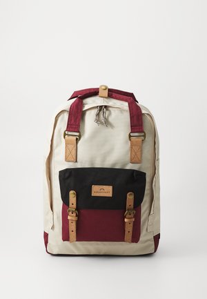 Kreem, burgundi ja musta värvi kanvaskott. Omab pruuni nahka aktsentides, reguleeritavaid rihmasid ning esist taskut klambritega.