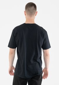 Black cotton T-shirt with short sleeves and a crew neck. Back view reveals a loose fit and smooth texture, with no visible patterns or accents.