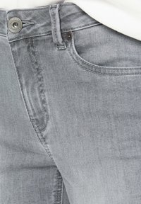 Helle graue Denim-Jeans mit glatter Textur, klassischen Knopfverschluss und traditionellem Fünf-Taschen-Design.