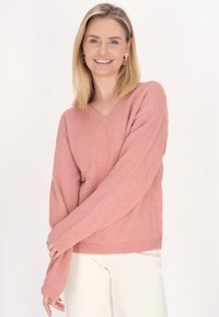 Helles rosa, leichtes Sweatshirt mit V-Ausschnitt und langen Ärmeln. Gestrickte Textur und gerippte Bündchen. Schlicht, lockere Passform.