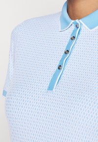 Jasnoniebieska koszulka polo z teksturowanym wzorem, z klasycznym kołnierzykiem i trzema guzikami, w tym metalowymi.