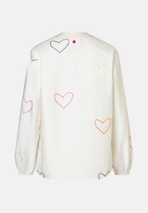Weißes Langarmshirt mit mehrfarbig gestickten Herzumrissen, die auf dem Rücken und den Ärmeln verteilt sind, mit einem kleinen pinken Knopf nahe am Kragen.