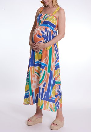 Robe maxi colorée avec un tissu texturé, présentant un mélange de motifs géométriques orange, bleu, vert et jaune, et de larges bretelles.