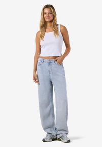 Šviesiai mėlynos plačių kojų džinsai iš džinso audinio, derinami su balta ribuota palaidine be rankovių. Apranga pasižymi laisvu siluetu ir laisvalaikiu stiliumi.