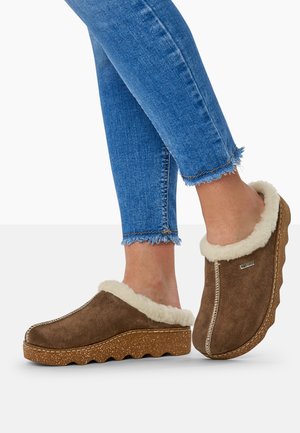 Brune ruskindsklipklapper med en blød hvid pelsforing, tekstureret gummisål og kontrasterende syninger. Båret med cropped blå jeans.