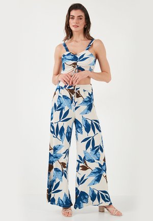 Completo a due pezzi con un top corto a fantasia con foglie blu e marroni e pantaloni a gamba larga, realizzato in un tessuto leggero e testurizzato.