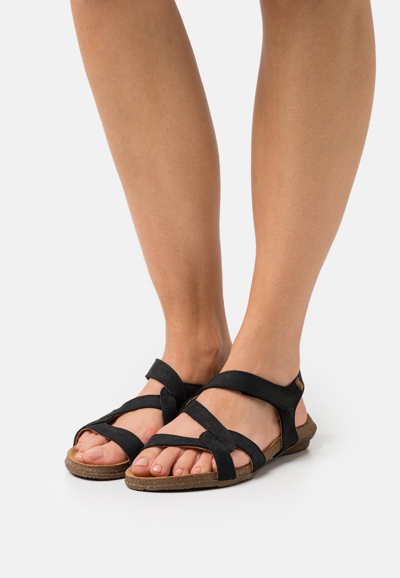 Černé textilní sandály s několika překříženými pásky a polstrovanou podrážkou. Mají strukturovanou stélku a plochý profil.