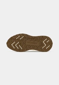 Rubber shoe outsole featuring a textured brown surface with zigzag and chevron patterns; embossed Lacoste logo in the center.