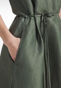 Grön linnéklänning med midjeband, sidoficka och texturerat tyg med naturlig glans. Detaljerad med rena sömmar och avslappnad passform.