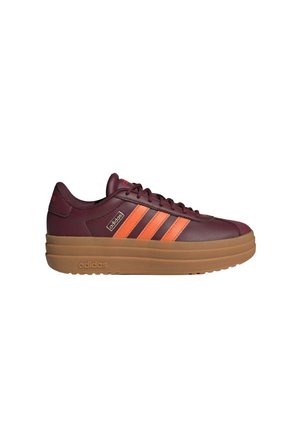 Scarpa da ginnastica Adidas color mogano con strisce arancioni, design con lacci e suola spessa marrone, vista laterale su sfondo bianco.