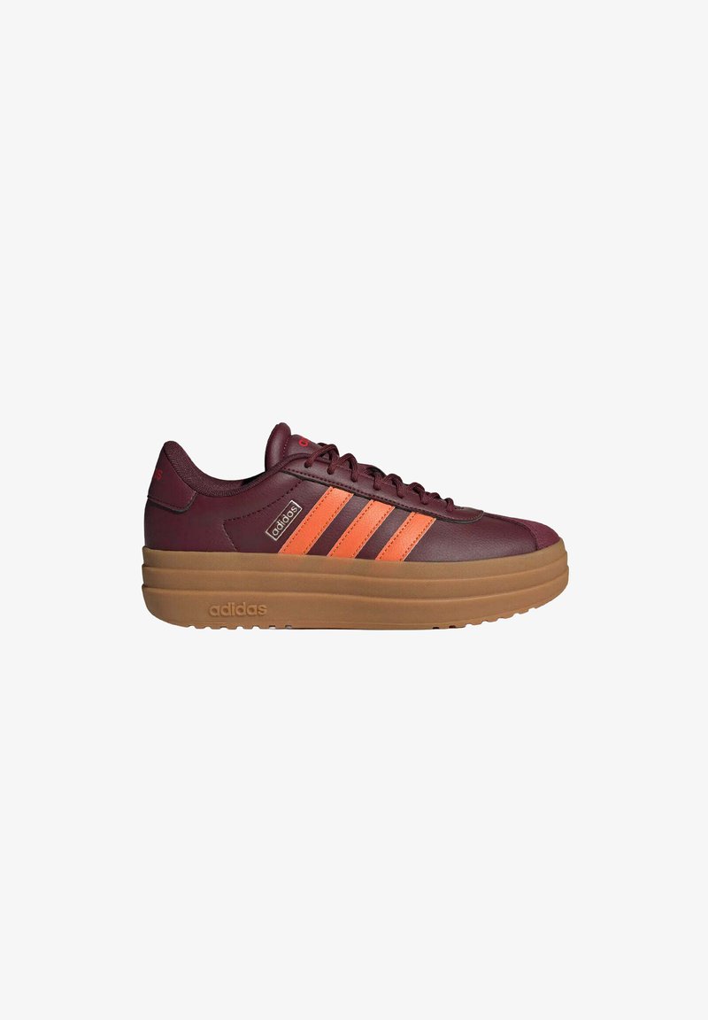 Baskets Adidas marron avec des rayures orange, design à lacets et semelle épaisse marron, vue de côté sur fond blanc.