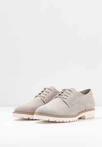 Scarpe in suede grigio chiaro con finitura liscia, design con lacci e suola in gomma bianca testurizzata caratterizzata da un motivo di battistrada robusto.