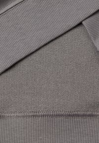 Textile gris présentant deux motifs : un tissu tricoté lisse avec un bord côtelé et une surface texturée avec des lignes horizontales.