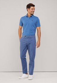 Camisa polo azul de manga corta con un bolsillo, combinada con chinos azul claro y zapatillas blancas, con un corte relajado y una tela suave.