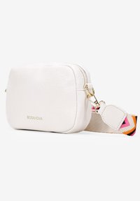 Bolso cruzado de cuero blanco con forma rectangular, cierre de cremallera y una correa de tela con un patrón colorido que presenta diseños geométricos.