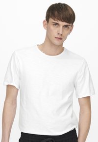 Witte T-shirt met korte mouwen en ronde hals, gemaakt van lichtgewicht stof, met een licht gestructureerd oppervlak en opgerolde mouwranden.