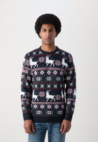 Suéter de malha azul-marinho com renas brancas, flocos de neve e padrões de diamante em vermelho e verde. Gola redonda e punhos canelados.