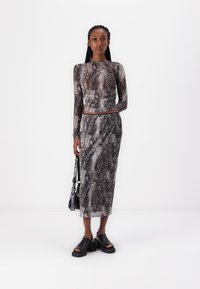 Conjunto de blusa de manga longa e saia em padrão de cobra, apresentando um design ajustado, textura transparente e sapatos de plataforma pretos chunky. Inclui uma bolsa preta.