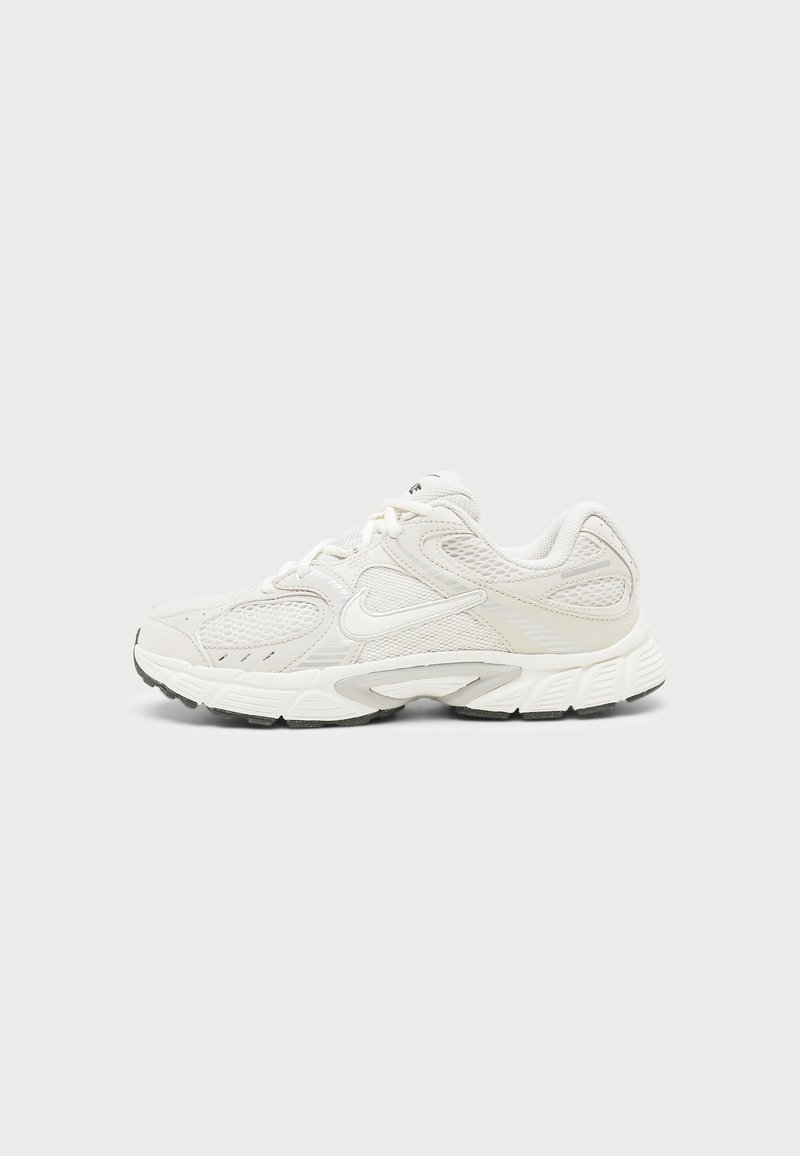 Λευκό αθλητικό παπούτσι Nike με επάνω μέρος από δίχτυ και συνθετικό υλικό, μαλακή σόλα και μαύρη εξωτερική σόλα, εμφανιζόμενο από το πλάι σε φωτεινό φόντο.