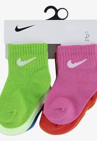 Ankelstrømper i lys grøn, pink og rød. Fremstillet af et glat strikket stof med hvide Nike-logoer på hvert par. Pakket på en bøjle.