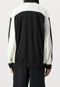 Schwarz-weiße Jacke mit hohem Kragen, elastischen Bündchen und glatter Textur, mit einem farblich abgestuften Design und entspannter Passform.