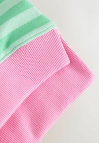 Pamuk tkanina u prugama u zelenoj boji s rebrastom ružičastom manšetom. Zelena boja ima naizmjenične svijetle i tamne pruge, što pokazuje mekanu teksturu.