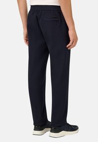 Pantalones deportivos azul marino, con un corte holgado, cinturilla elástica y un discreto bolsillo trasero con cremallera para un almacenamiento seguro.