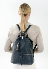 Zaino in pelle nera con chiusura a coulisse, maniglie superiori e spallacci regolabili, dotato di una tasca frontale con zip e dettagli con nappina.