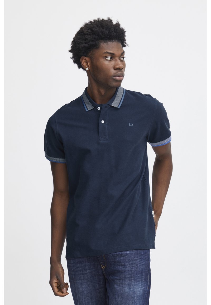 Marine polo-shirt med krave, to knapper og kontrasterende lyseblå stribede detaljer på manchetterne og kraven.