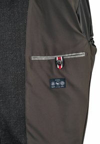 Interne zak van een grijze jas met knoopsluiting, voorzien van een rood, wit en blauw label, en een H-ECO label dat aangeeft dat het gemaakt is van gerecycleerde, duurzame, milieuvriendelijke materialen.