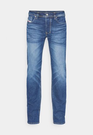 Blå slim-fit denim jeans med falmet effekt, frontknap, lynlås lukning og fem-lomme design på en hvid baggrund.