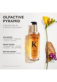 Kérastase Elixir Ultime, a transparent bottle with a gold pump, contains a golden liquid. Accompanied by yellow and purple flowers on a light background.