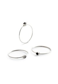 Tre minimalistiske sølvringe med sorte og klare sten indlagt i glatte, rundede bånddesigns. Hver ring har en enkel, udsmykningsløs facon.