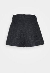 Shorts noirs en tissu texturé avec un motif tissé. Caractéristiques d'une taille haute et d'une coupe droite, sans fermetures ni poches visibles.