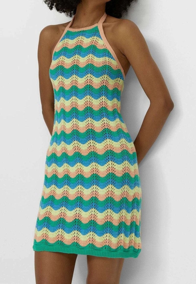 Robe en tricot avec un col halter présentant un motif ondulé en bleu, vert, pêche et jaune. Fil de coton texturé et ourlet vert uni.