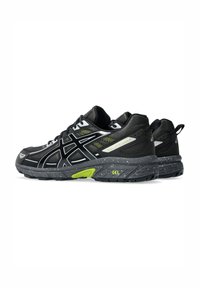 Black athletic shoes with a textured upper, reflective silver and neon green accents, and a speckled gray outsole featuring gel cushioning.