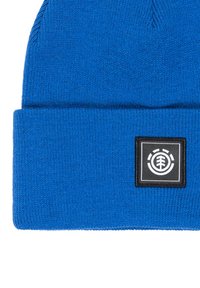 Berretto lavorato a maglia blu realizzato in materiale morbido, con una toppa quadrata nera e un logo bianco. La texture è liscia e presenta un design con risvolto.