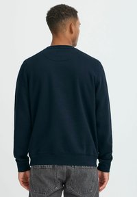 Marineblaues Sweatshirt mit Rundhalsausschnitt, gerippten Bündchen und Saum. Aus weichem Stoff gefertigt, mit glatter Textur und minimalistischen Design.