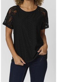 Svart topp med korta spetsärmar och texturerad tyg med diamantformade utskärningar. Avslappnad passform med rundad nederkant och krage.