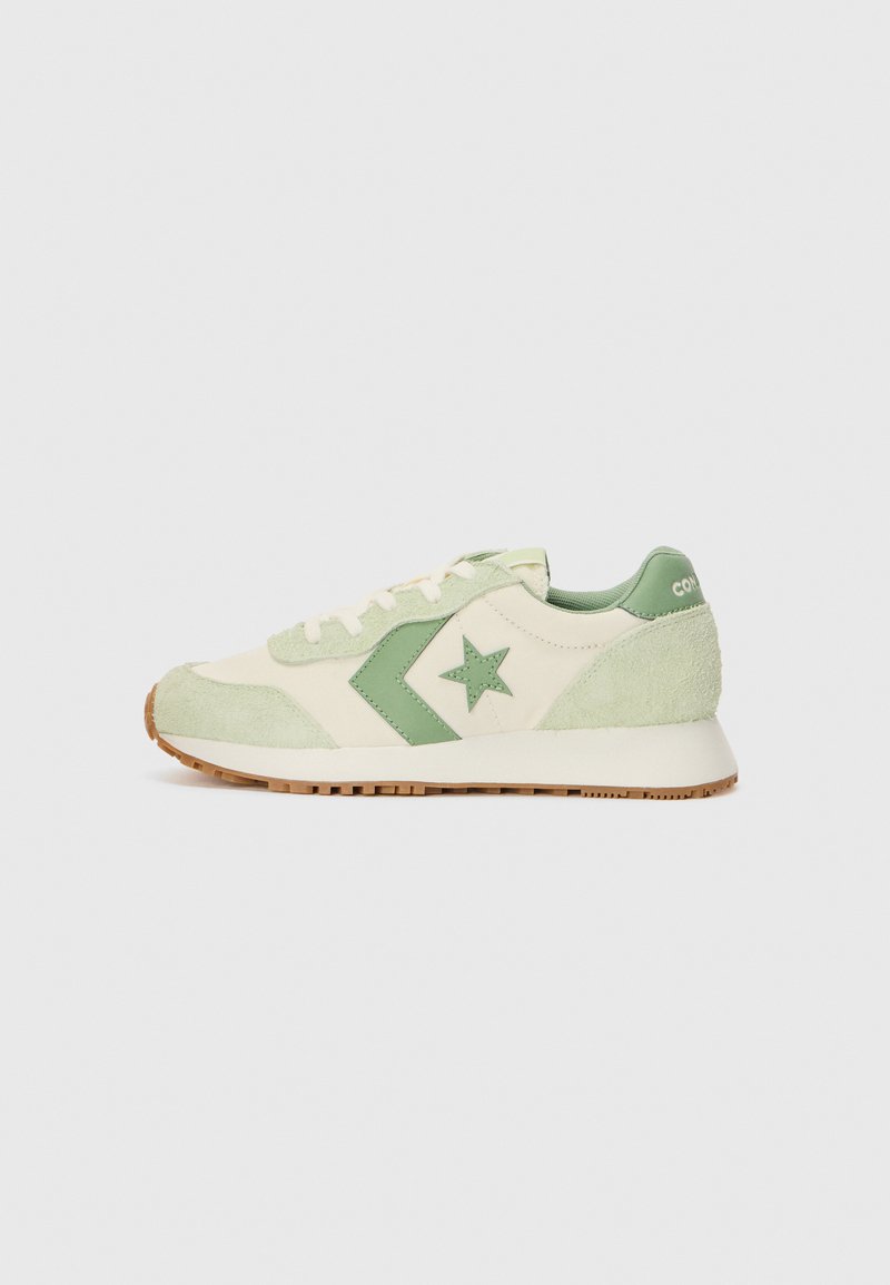 Krem og lysegrønn sneaker laget av semsket skinn og tekstil. Har en stjerneakcent, kontrastfarget grønn logo og en strukturert gummisåle.